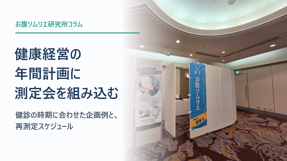 お腹ソムリエの「測定会開催中」ののぼりとタペストリーが立つ測定会場と、記事タイトル「健康経営の年間計画に測定会を組み込む——健診の時期に合わせた企画例と、再測定スケジュール」
