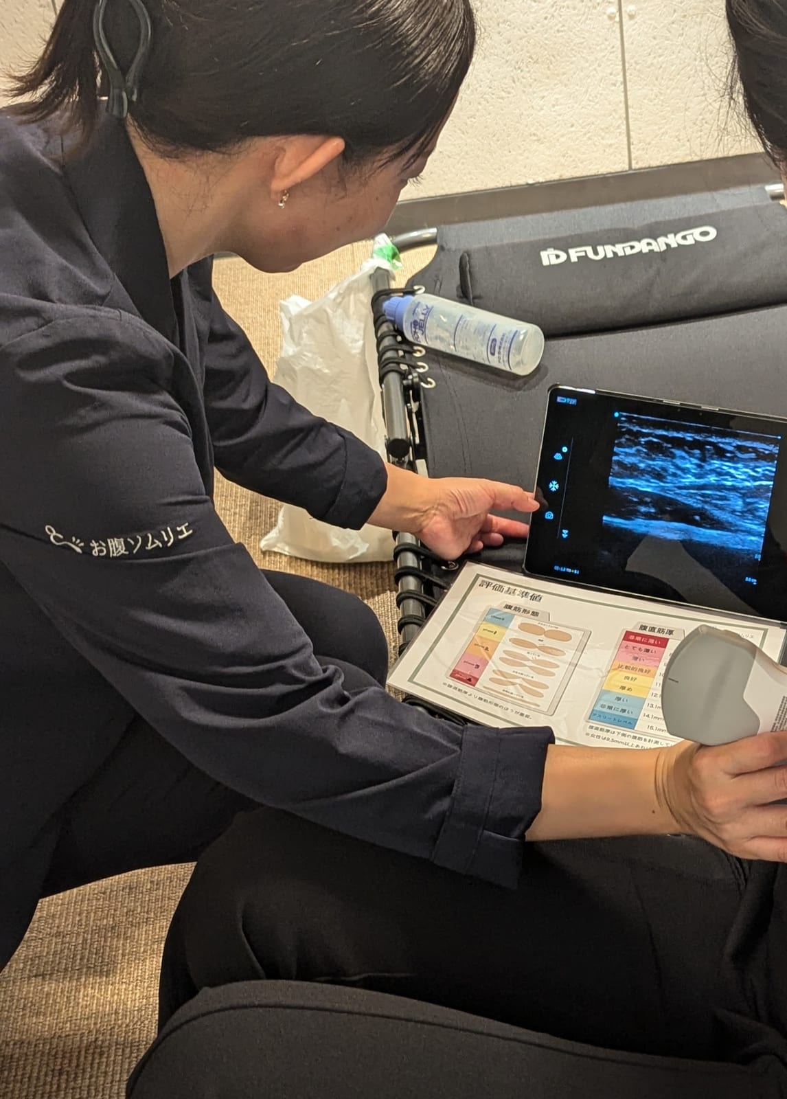 評価シートとタブレットを使って測定結果を説明する様子。健康経営の取り組みの実施イメージ